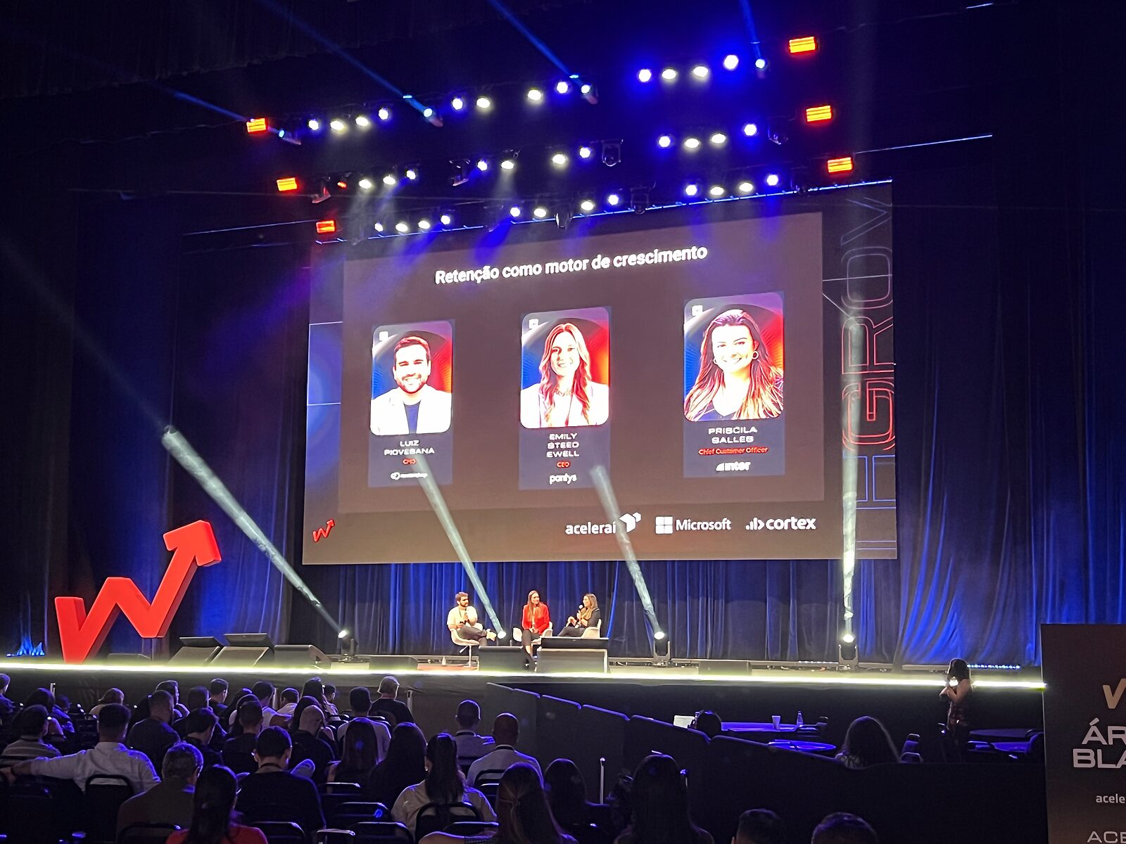 Palco com telão, iluminação e plateia em evento